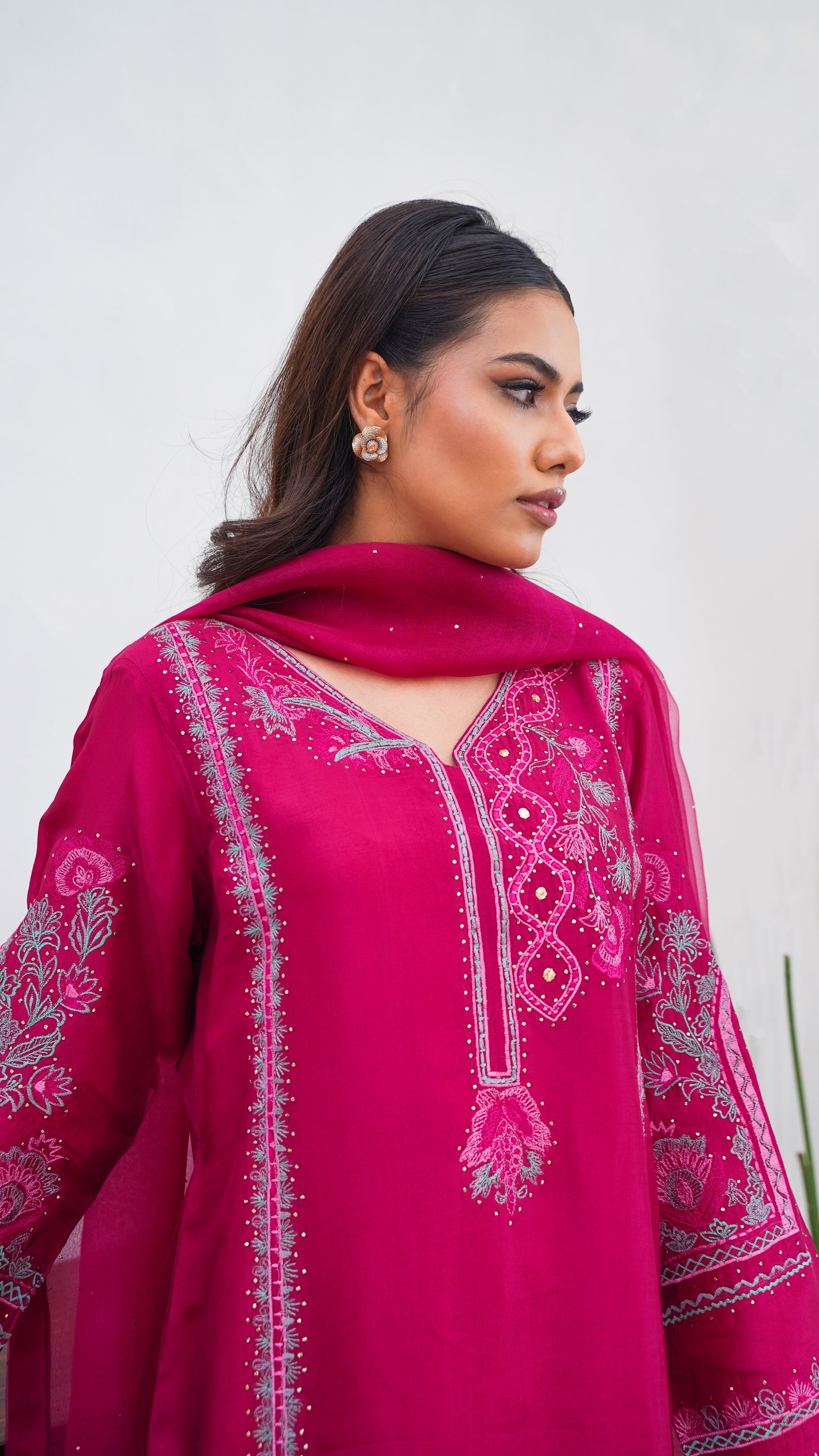 Woman wearing a pink embroidered traditional outfit against a white background